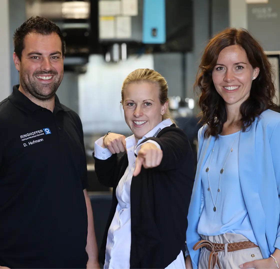 Daniel Hofmann, Romina Doster, and Nina Ringhoffer smile for the camera on the production floor