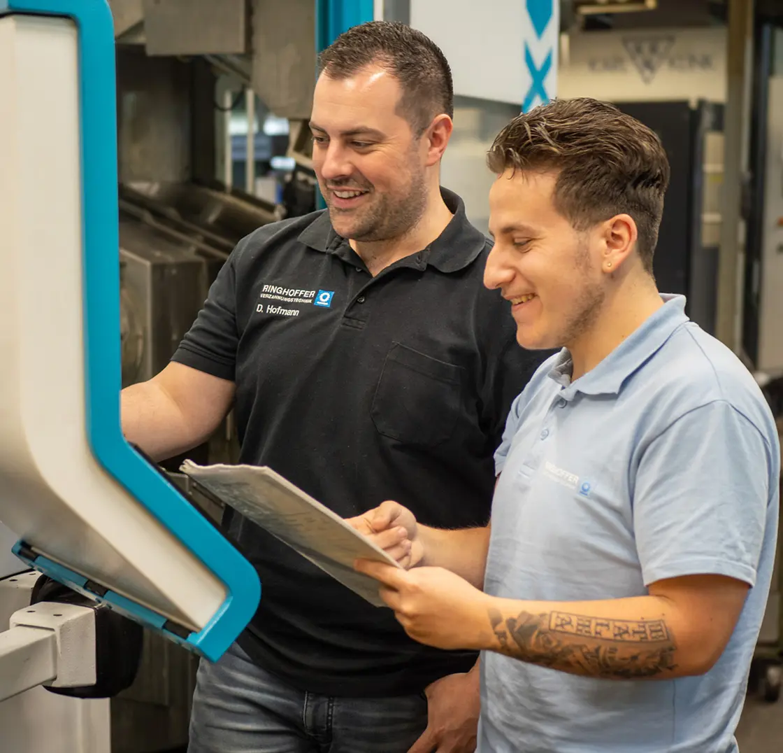 D. Hofmann is discussing a technical drawing with an employee at the CNC machine