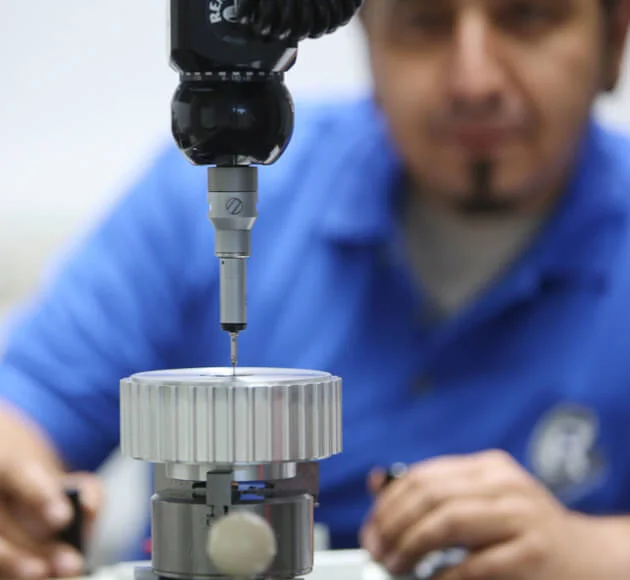 An employee monitors the coordinate measurement of a gear using a probe
