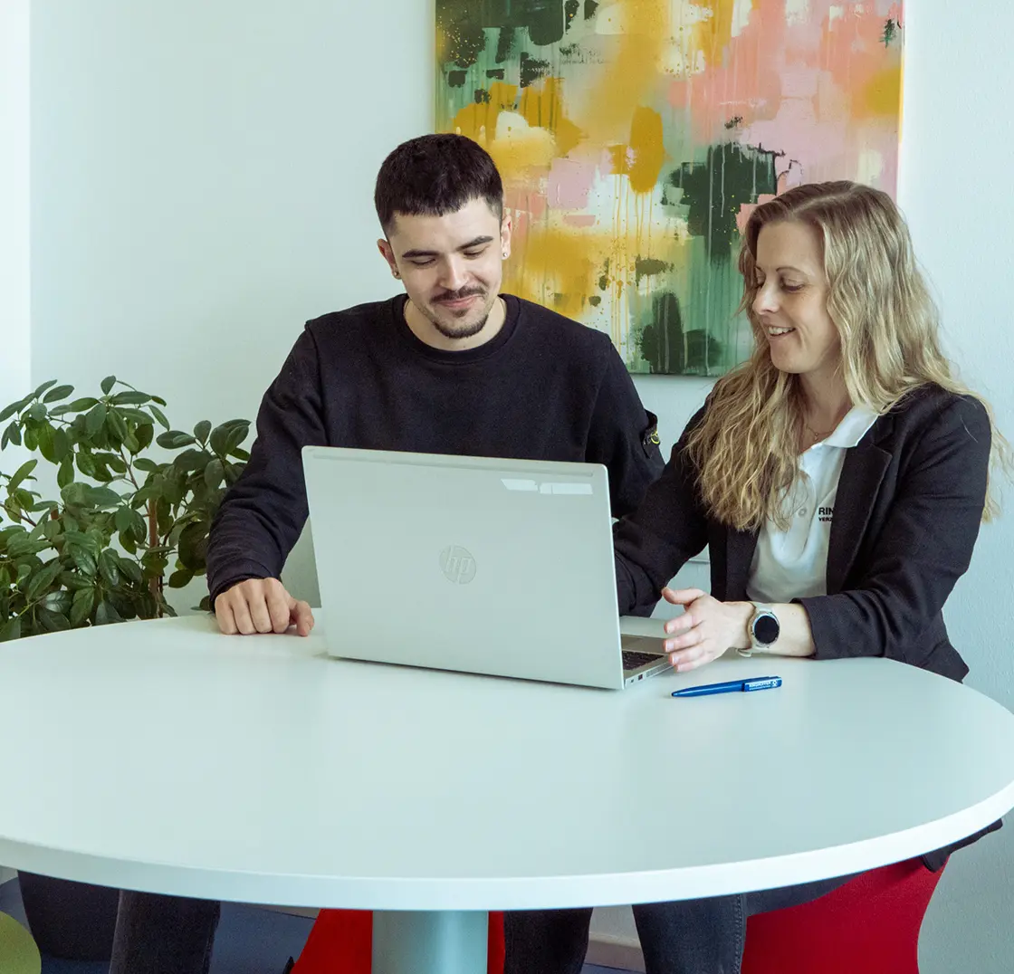Two employees discussing something together on a laptop in the office
