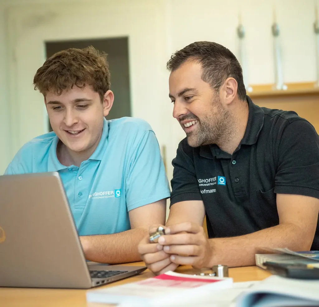 Hofmann und ein Auszubildender arbeiten gemeinsam am Laptop im Schulungsraum