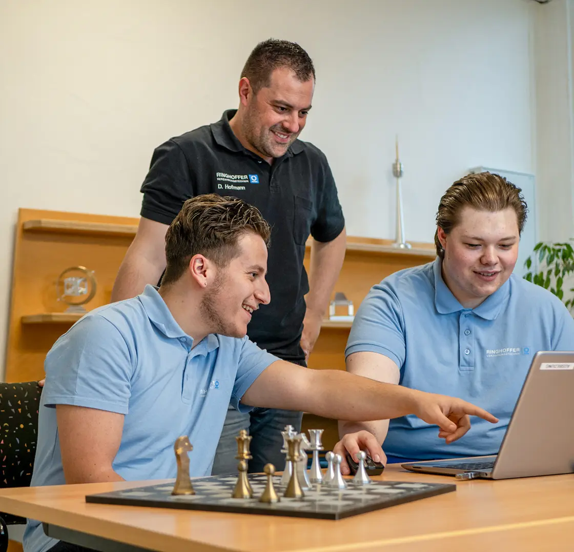 Daniel Hofmann is helping two trainees as they work on their laptops in the training room